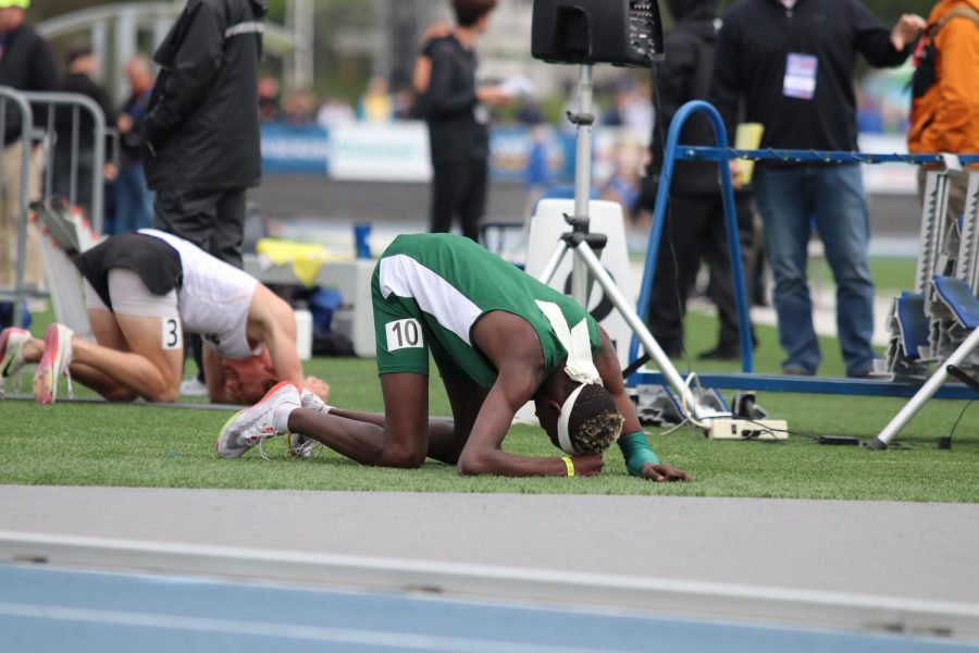 Freshman Moustafa Tiea collapses on the ground after securing eight place and recording a personal record in the 800 meter run.
