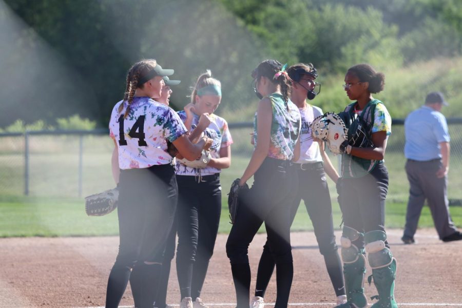 The softball team huddles together during the first inning against City High on June 22, 2022.