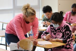 Math teacher Gelene Smutz helps Alexandria Filerio 23 with math problem on pink out day. 