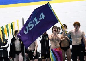 The boys swim team waves a flag saying OS14 to remember their late teammate Owen Skelley