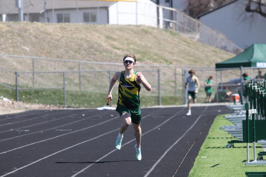 Junior Aidan Jacobsen runs the 400-portion of the distance medley at the track meet on Apr. 8, 2023.