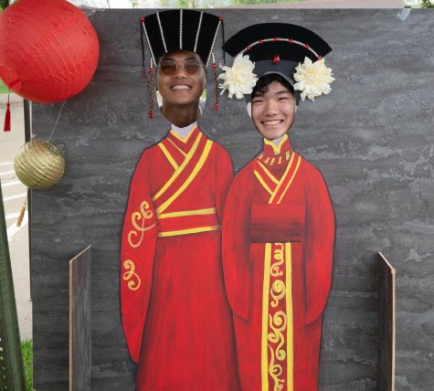 Derek Hua 25 and Nathan Chen 23 pose in cuts outs of traditional Chinese clothing at Asian Fest 2023.
