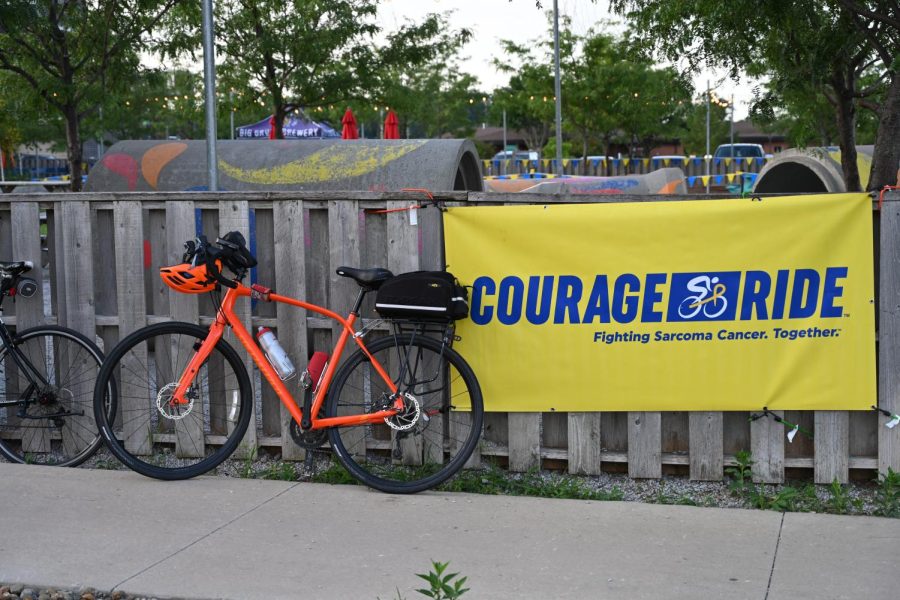 A bike leans against a fence next to a Courage Ride banner