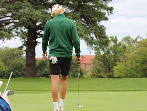 Cole Collier walks on the golf course, preparing for his next swing.