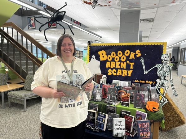 Jill Hofmockel stands in front of a Halloween themed book stand.