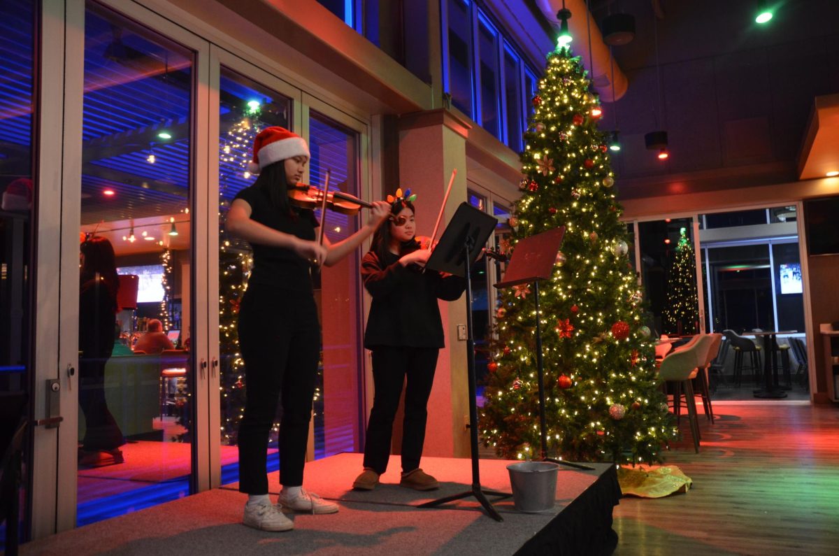Juniors Anjali Lodh and Anna Song play a violin Christmas duet at Vue Rooftop Dec. 19.