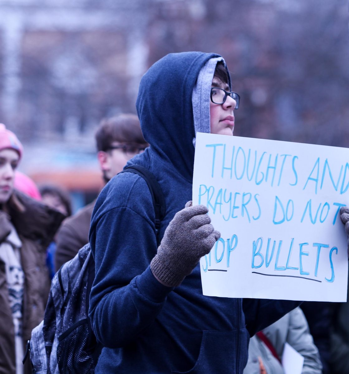 A City High student holds up a sign that reads Thoughts and prayers do not stop bullets at the protest on Jan. 8, 2024.
