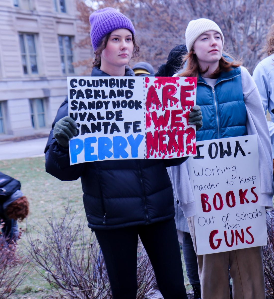 City High students hold up signs in the front row of the protest on Jan. 8, 2024. There were many signs with messages for the Iowa legislature, such as Working harder to keep books out of schools than guns. 