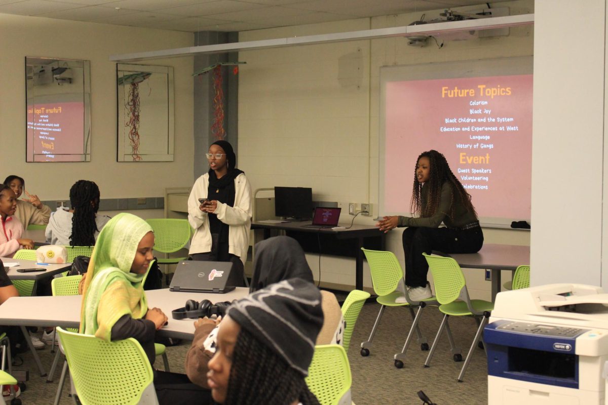 Rawan Babiker '25 and Neema Ash '25 talking to group of students in the library