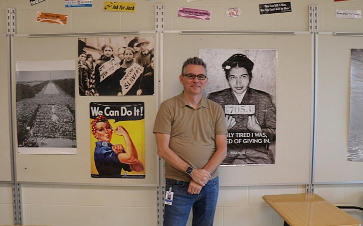 Steven Caulk stands with his posters in his classroom.