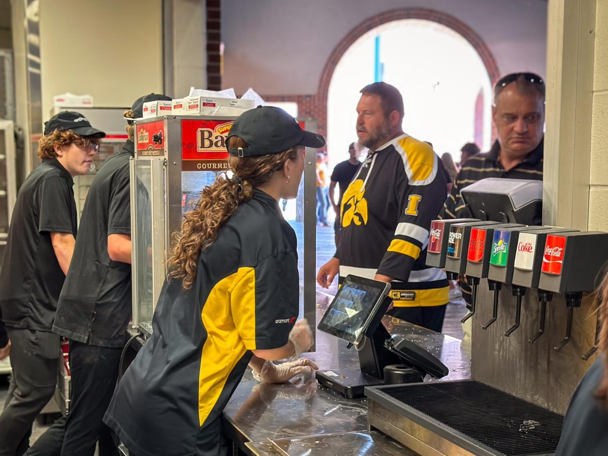 Lydia Evans '26 talks with a customer while volunteering at Kinnick Stadium on Sept. 7 to fundraise money for the Symphony Strings.