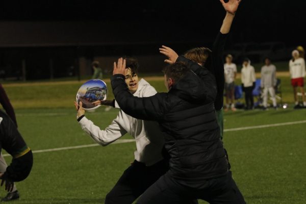 Sidney Westgard '25 attempts to throw a frisbee past two defenders