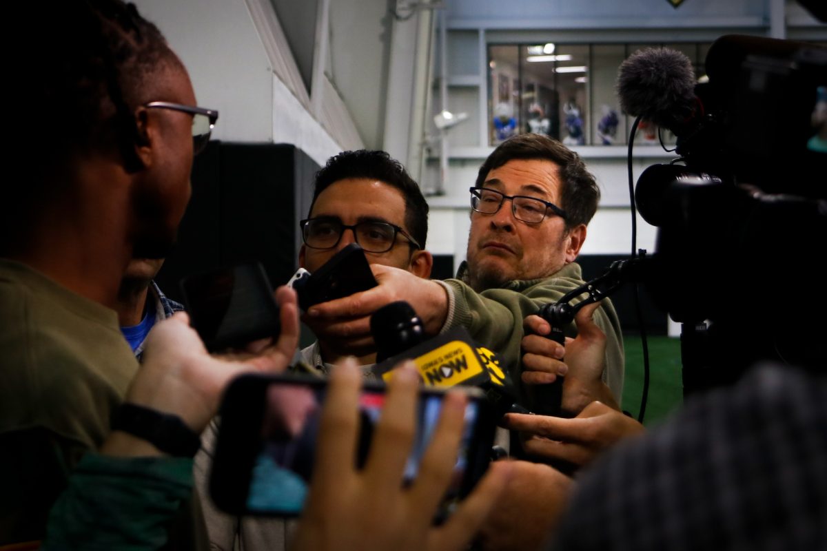 Professional journalists from around the community surround Jermari Harris, a cornerback for the University of Iowa