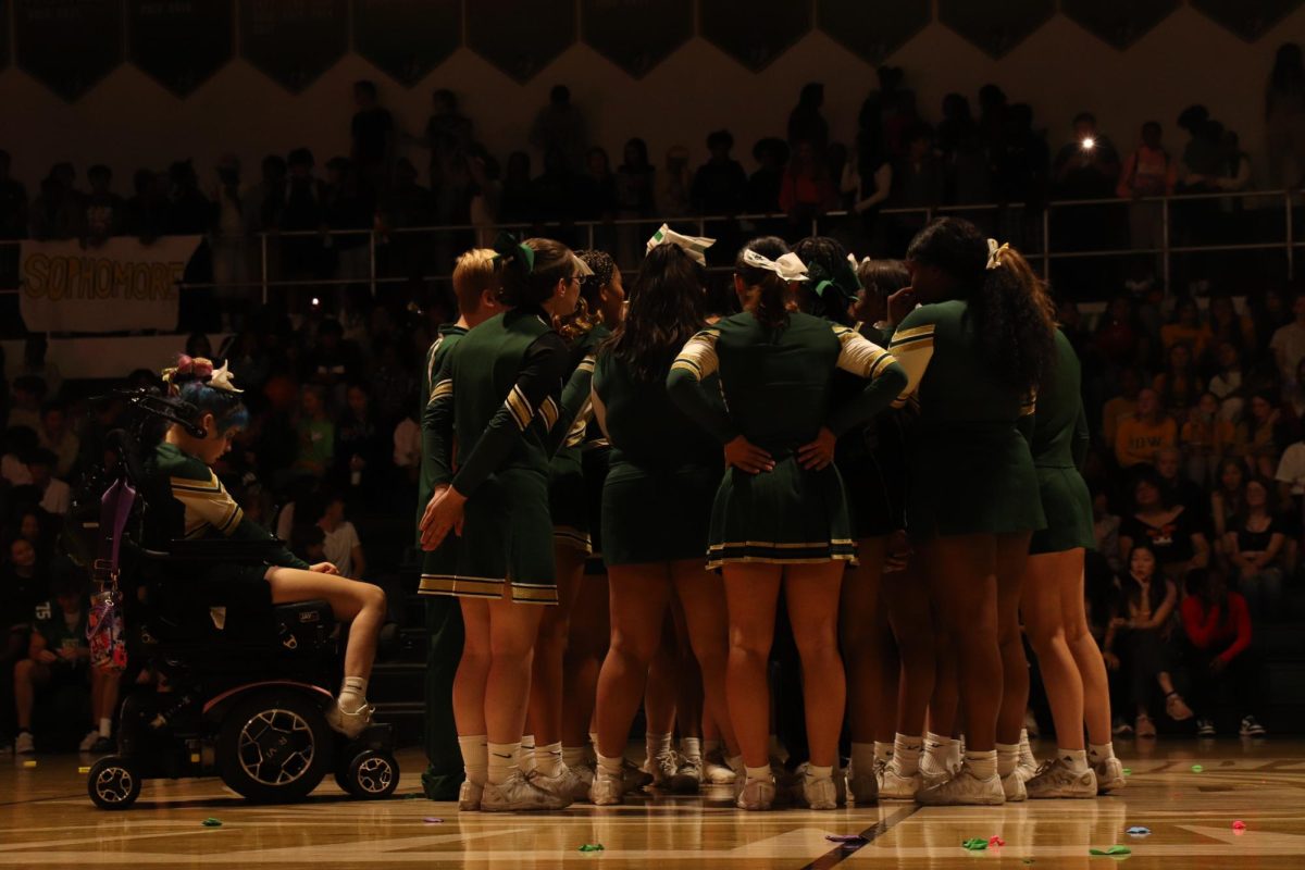 The cheer team huddles together to discuss plans for their stunt.