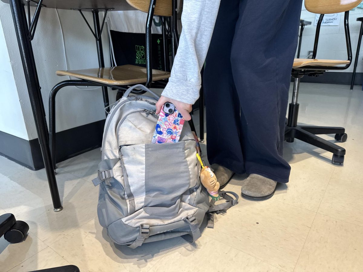 A student places their phone in their backpack.