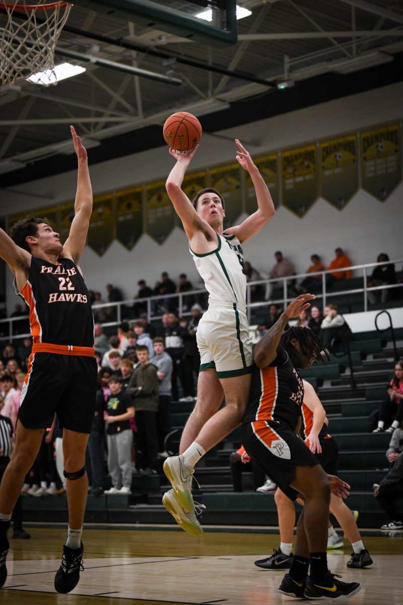 Splitting two defenders, Jack McCaffery '25 shoots a turnaround jump shot in the North Gym. On Jan. 17, McCaffery led the Trojans in points and rebounds.