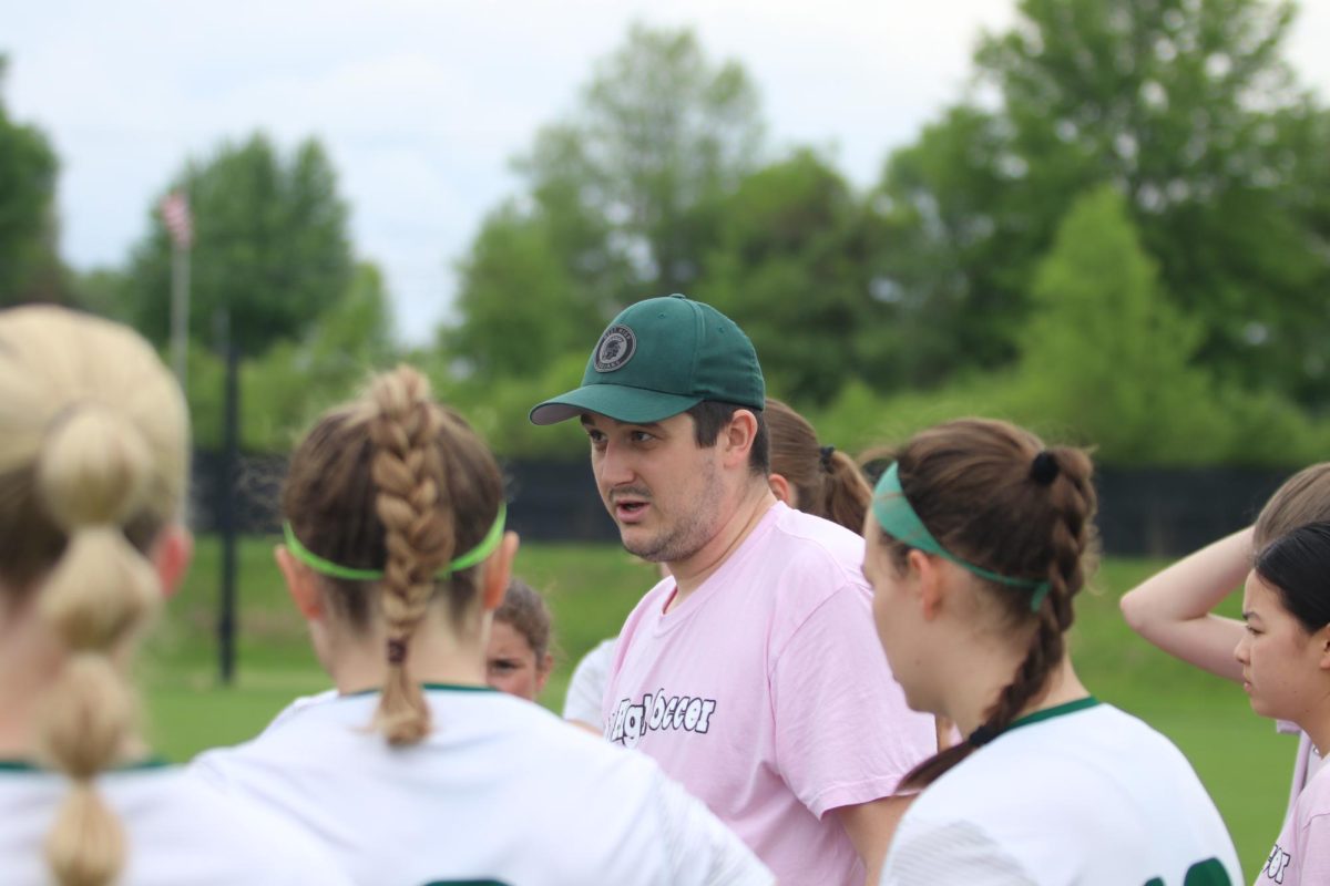 Girls soccer head coach, Zachary Serovy, leads the huddle in West High's matchup against City High.