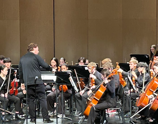 Director Jon Welch cues Symphony Strings principal cellist Ellie Roetlin '26 for her solo.