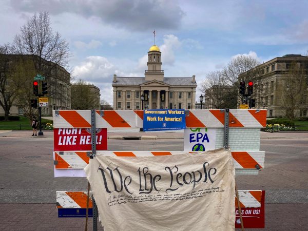 Placed in between the Old Capitol Museum and Iowa Avenue, a barricade stands to separate the demonstration and traffic April 22, with the preamble of the U.S. Constitution draped over it. Later, demonstrators signed this preamble in protest of current government policies, such as mass deportations and contentious following of legal orders.