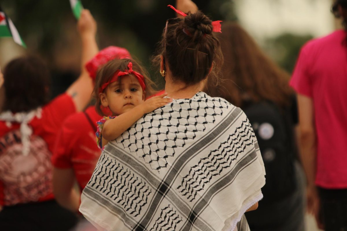 On June 7, demonstrators in downtown Iowa City gathered to protest the continued funding the United States provides to Israel. During the march, a young girl, holding onto her mother’s keffiyeh, stares straight into the camera.

