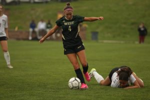 Paz Martinez '25 turns past a Western Dubuque player as she falls to the ground from Martinez's fake.