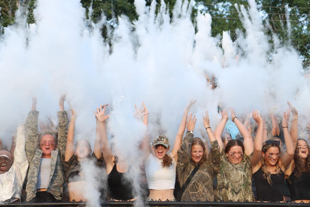 The West High student section throws baby powder into the air as the football players get ready for kickoff.