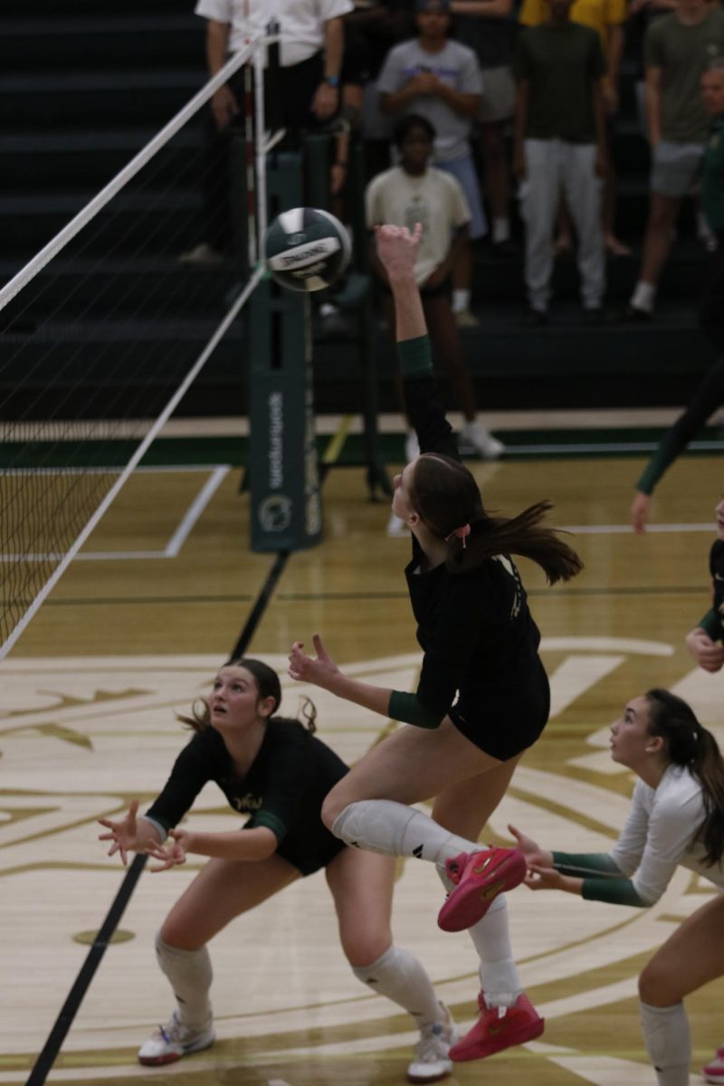 Cyan Blommer '29 hits the ball while her teammates cover her block.
