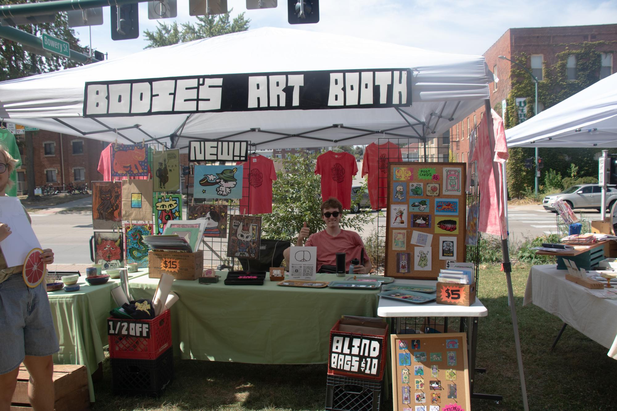 Bodie Williamson '22 poses in front of his art booth at the flea market. Williamson has been selling at the flea market since he was in high school. 