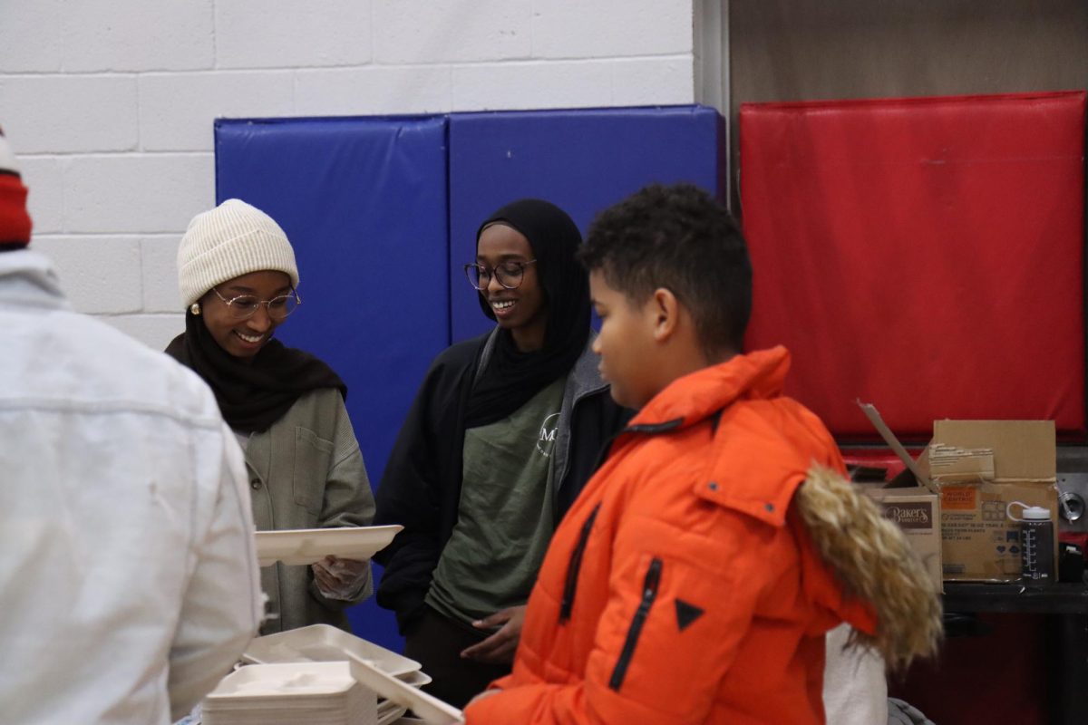 Two members of Mariam Girls Club distribute food during the community meal Dec. 12.
