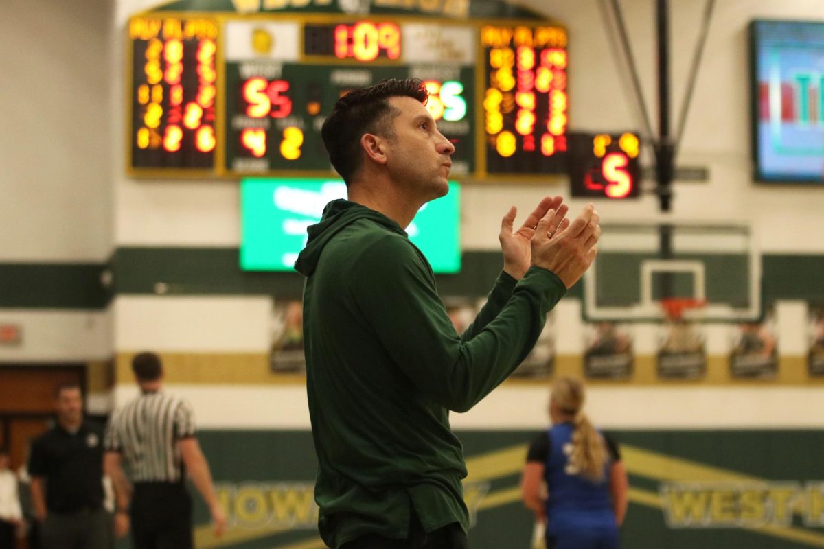Coach Nate Freese applauds the Trojans good play