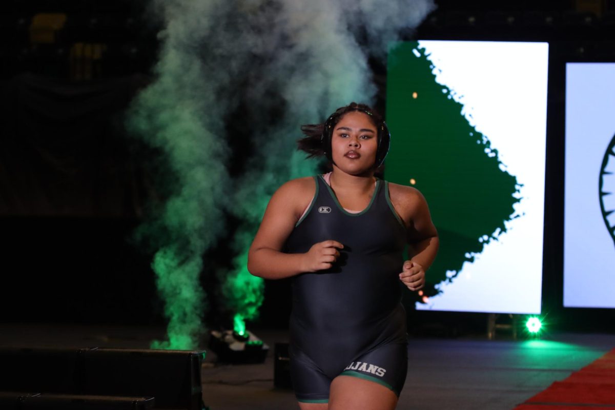 Amira Vazquez ‘29 runs out to the mat to accept her forfeit at 235 pounds. The forfeit gave the Trojans the points they needed to come out on top, defeating City High 42-39 Dec. 18.