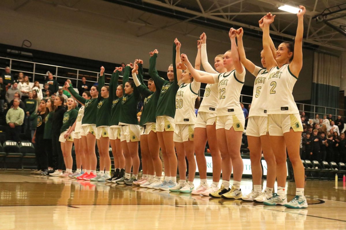 The girls basketball team raises their arms after the national anthem before their game against CCA