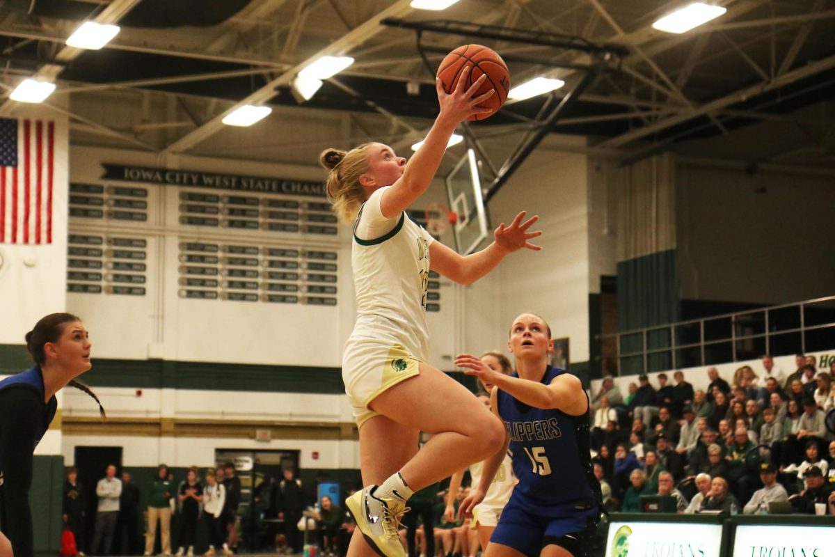 Grace Fincham ’27 steals the ball from the Clear Creek Amana Clippers and dribbles down the court before leaping towards the rim for a layup and two points.