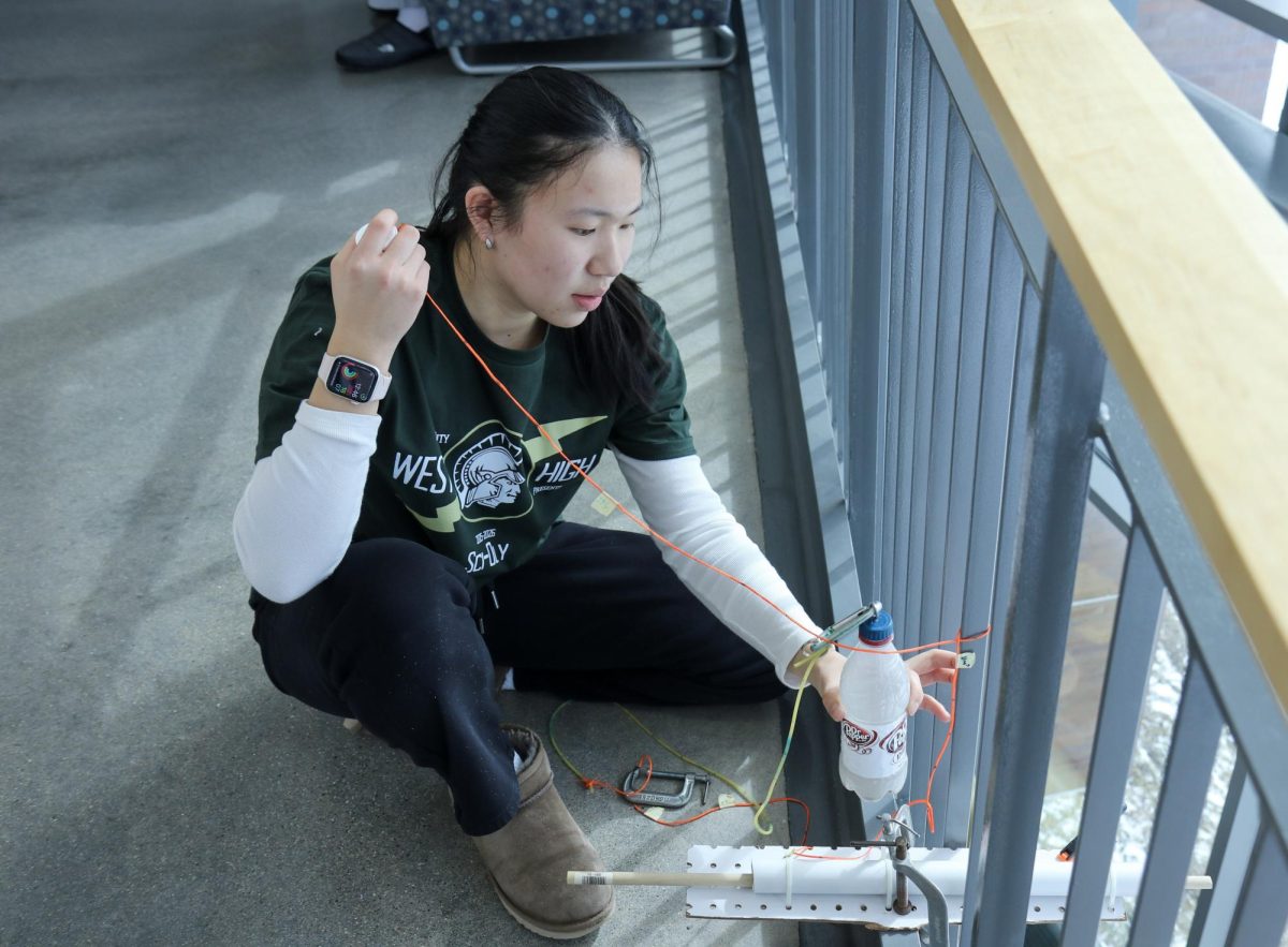 Erin Chen '27 pulls the string during the Bungee Drop event at the Mount Vernon Invitational Feb. 21. Bungee Drop is one of many build events, where students create machines to fulfill certain objectives. “There's so many unknowns, so many variables. Because it takes a long time to build [the individual parts] and calibrate your things, it's stressful going in and knowing that [it] could go wrong, and that work was for nothing,” Chen said. 