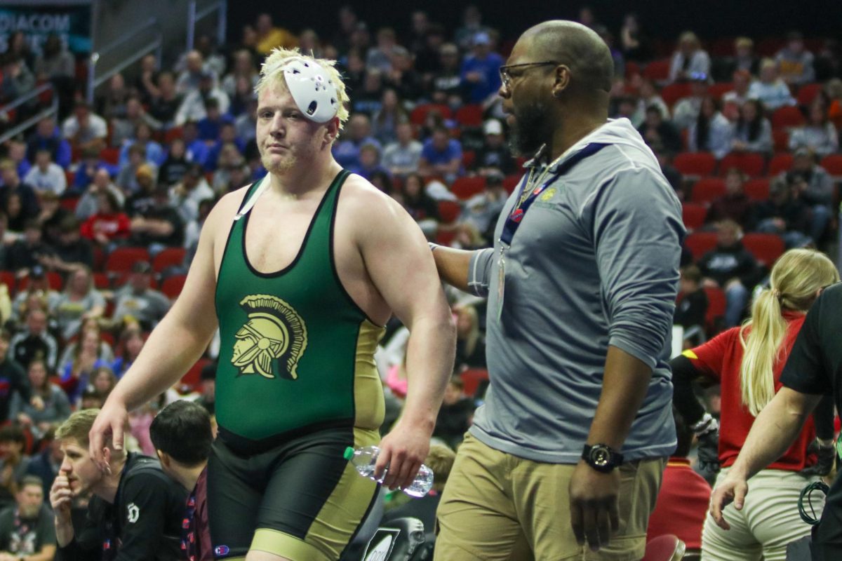 Senior Kaden Stitt walks off the mat with his coach after a victory Feb. 20.