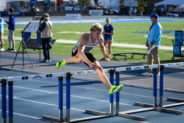 Leaping over a hurdle, Ryder Gorsh '26 runs the anchor leg of the 4x110m shuttle hurdle relay at Drake Stadium April 25. The relay took first, setting a national record of 55.82.